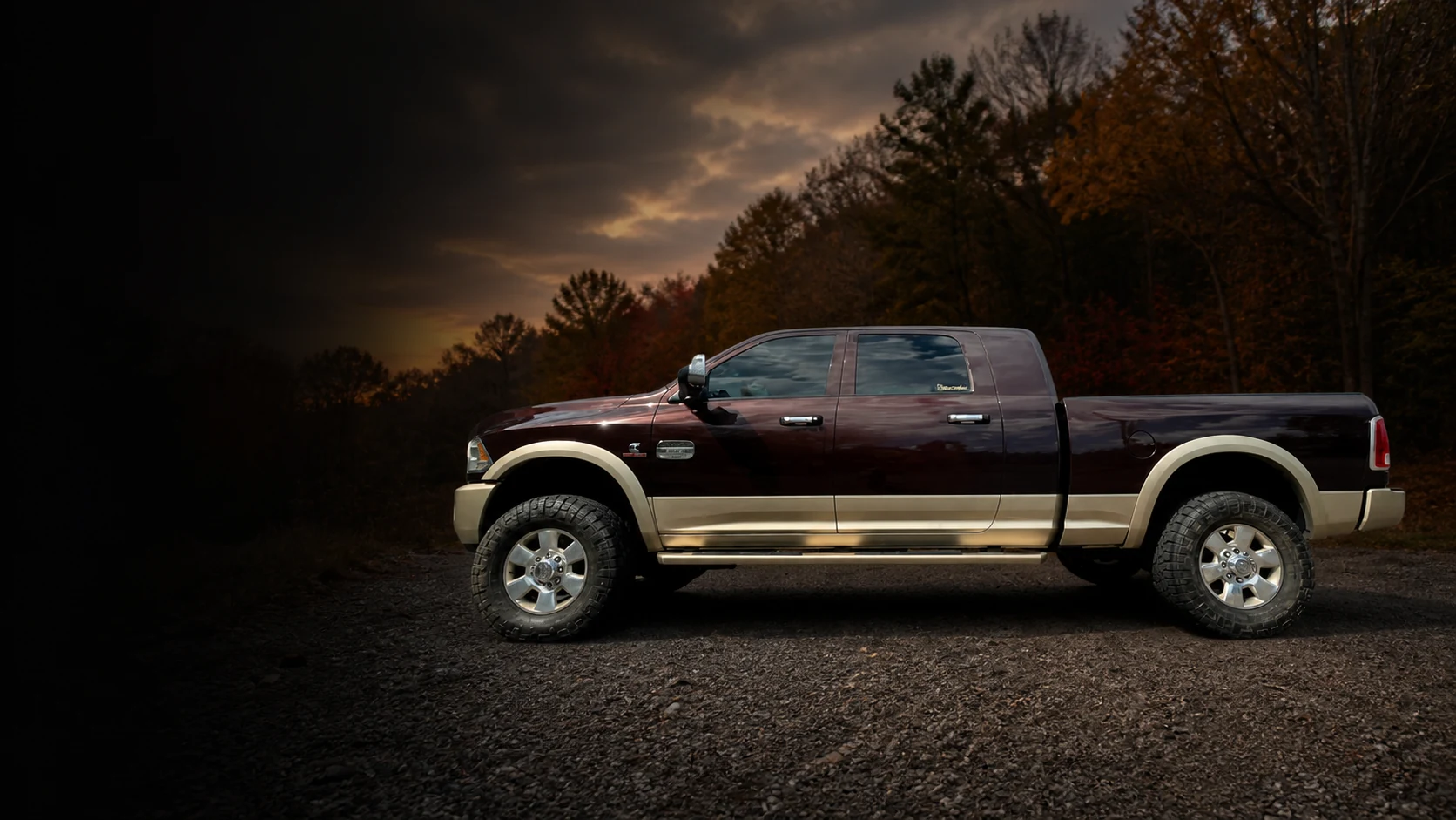 Burgundy and champagne Dodge Ram pickup on a rural gravel turnout at dusk